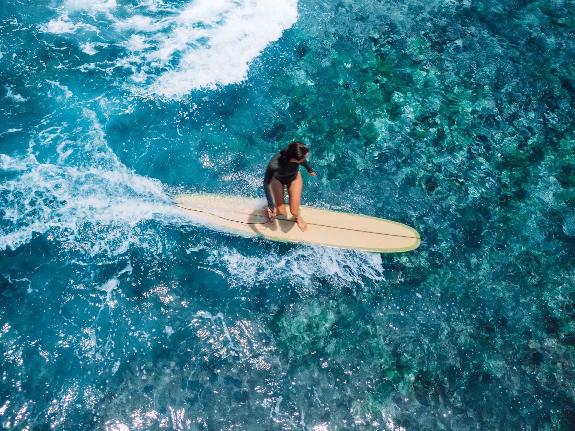 Woman rides on longboard on ocean wave. Drone view of woman during surfing