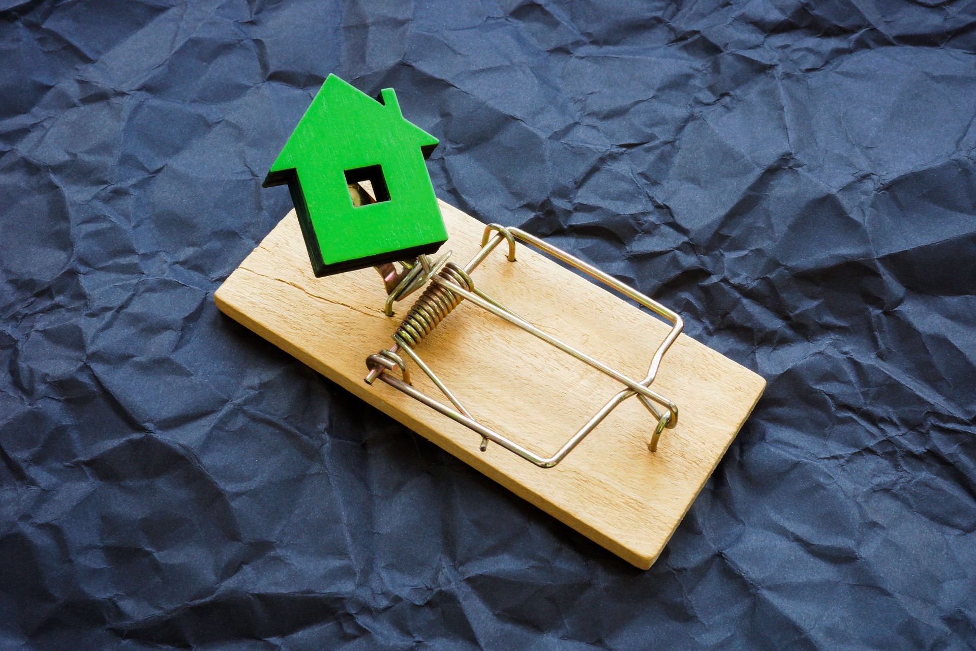 Small house trapped as a symbol of real estate fraud.